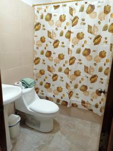 y baño con aseo y cortina de ducha. en Las Orquideas ( Rural house ) en Cumanda