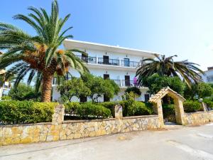 a large white building with palm trees and a stone wall at Panorama in Agios Georgios