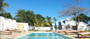 a pool with chaise lounge chairs and a group at We Call it Home - Bububu Villa in Mtoni