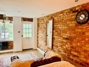 un soggiorno con muro di mattoni e orologio di East Bridgford Coach House Inc Spa and Treatments a East Bridgford
