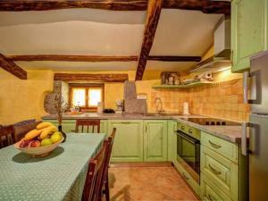 - une cuisine avec des placards verts et une table avec un bol de fruits dans l'établissement Holiday House Kapitani, à Hum