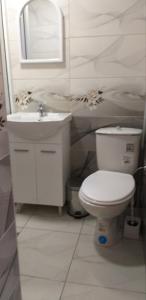 a white bathroom with a toilet and a sink at Стаи за нощувки in Sliven