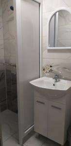 uma casa de banho branca com um lavatório e um espelho em Стаи за нощувки em Sliven
