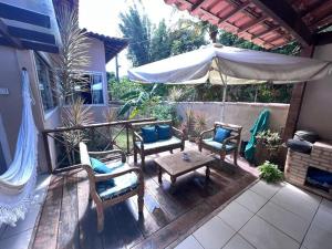 a patio with chairs and a table and an umbrella at Casa Recanto de Manguinhos in Búzios