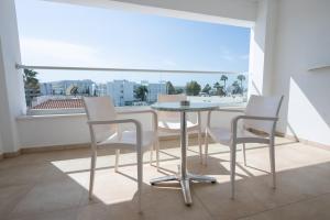 a table and chairs in a room with a large window at New Famagusta Hotel & Suites in Ayia Napa