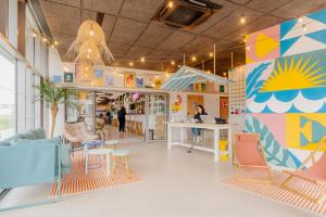 a room with chairs and tables and a colorful wall at The People Caen in Caen