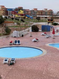 een zwembad met ligstoelen en parasols en 2 zwembaden bij Appartment - Porto Sharm El Sheikh - Chalet 61205 B in Sharm El Sheikh