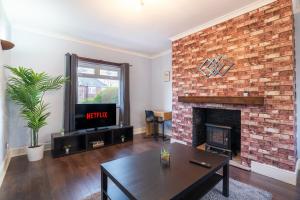 a living room with a brick fireplace and a tv at Stylish 3 Bed House-Free Parking in Sheriff Hill