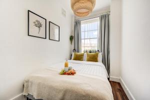 a white bedroom with a bed with fruit on it at The London Perfect Attic - sleeps 8 in London