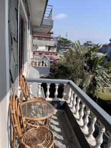 2 stoelen en een glazen tafel op een balkon bij Hotel Pokhara View backup in Pokhara