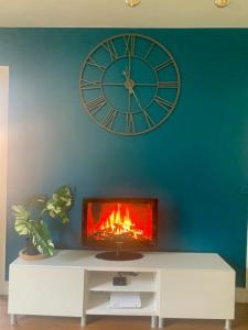 a clock on a blue wall with a fire in a tv at Pantin Paris in Pantin