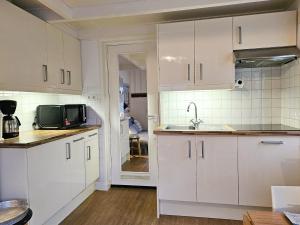 een keuken met witte kasten en een magnetron bij Vakantiewoning in het centrum van Domburg DO29 in Domburg