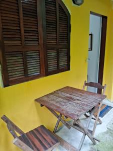 a wooden table and two chairs in front of a yellow wall at Pousada Familia Viva Trindade in Trindade