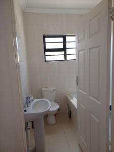 baño con lavabo y aseo y ventana en Lot 15168 Zeerust Road, en Tlokweng