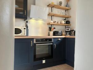 a kitchen with navy blue cabinets and a microwave at The Dale at Greystones - Luxurious annexe with stunning view in Buckden