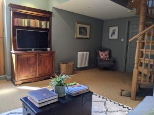 a living room with a television and a book shelf at Two Luxury Cosy Cottages in Tewkesbury