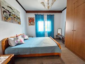 a bedroom with a bed with blue curtains and a window at Dreamer's Home Chrisa in Limenas