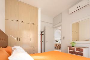 a bedroom with white walls and an orange bed and cabinets at Villa Apelia - Family Holidays Deals in Vlikhádha