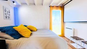 a bedroom with a bed with yellow and blue pillows at Futurostudio - Appart Hôtel LEGO - 5min du Parc Futuroscope - Parking - Poitiers in Chasseneuil-du-Poitou