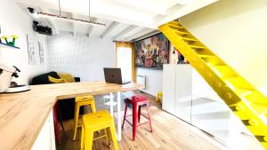 Cette chambre comprend un bureau et des tabourets jaunes. dans l'établissement Futurostudio - Appart Hôtel LEGO - 5min du Parc Futuroscope - Parking - Poitiers, à Chasseneuil-du-Poitou