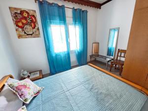 a bedroom with a bed with blue curtains and a chair at Dreamer's Home Chrisa in Limenas +17 photos