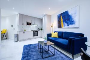 sala de estar con sofá azul y cocina en Hybrid Resi - Uxbridge, en Uxbridge