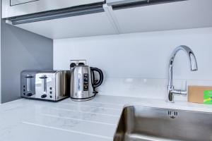 a kitchen counter with a sink and a microwave at Hybrid Resi - Uxbridge in Uxbridge