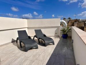 two chairs sitting on a patio on a roof at Mosta Dome Penthouse in Mosta