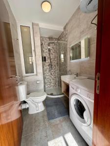 a bathroom with a toilet sink and a washing machine at Mosta Dome Penthouse in Mosta