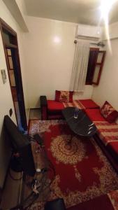 - un salon avec une télévision et un canapé rouge dans l'établissement Résidence Gharnata, à Marrakech