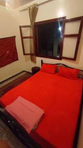 Cama roja en habitación con ventana en Résidence Gharnata en Marrakech