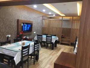 a dining room with tables and chairs and a tv at Le Tokyo Hotel Vithalapur in Vithalpur