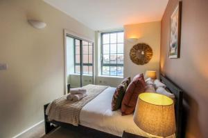 a bedroom with a bed with a lamp and a window at Modern 2 Bedroom Apartment by Train Station in Nottingham