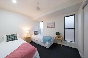 une chambre avec deux lits et deux fenêtres dans l'établissement Whitsunday Whisper Terrace - Townhouse Pets Airlie, à Airlie Beach