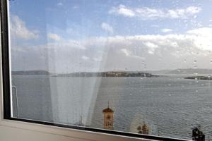 a window with a view of the water and a clock tower at The Sardinian Guesthouse (6 Bedrooms) in Cobh