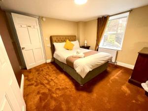 a bedroom with a bed with yellow pillows and a window at The Sardinian Guesthouse (6 Bedrooms) in Cobh