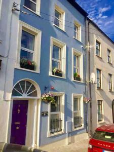 een blauw gebouw met bloemen in de ramen bij The Sardinian Guesthouse (6 Bedrooms) in Cobh