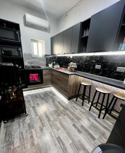 a kitchen with black cabinets and bar stools at Bookarest Hostel Malta in St Julian's