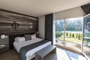 1 dormitorio con cama y ventana grande en Saint Malo Golf Resort, en Le Tronchet