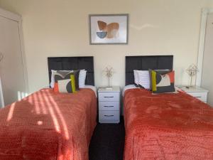 two beds in a bedroom with red sheets and pillows at Chepstow House (5 BR with FREE on-steet parking) in Newport