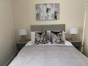 een slaapkamer met een bed met kussens en 2 lampen bij Chepstow House (5 BR with FREE on-steet parking) in Newport