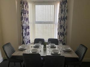 een eettafel met stoelen en een groot raam bij Chepstow House (5 BR with FREE on-steet parking) in Newport