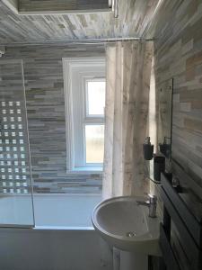 a bathroom with a sink and a tub and a window at Chepstow House (5 BR with FREE on-steet parking) in Newport