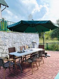 a table and chairs with a large green umbrella at Bloossom house in Bajina Bašta