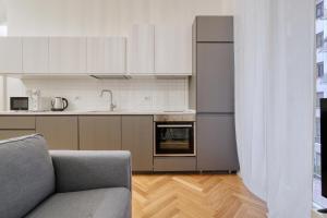 Il comprend une cuisine équipée d'un canapé et d'un réfrigérateur. dans l'établissement JOIVY Renovated Flat by Piazza Leonardo da Vinci, à Milan