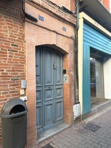a door on a brick building with a trash can at Le Rive Droite proche gare parking facile in Montauban