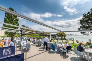 a restaurant with people sitting at tables on a deck at Harbour Hotel & Spa Christchurch in Christchurch
