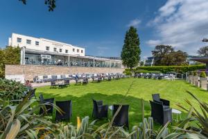 a lawn with chairs and tables in front of a building at Harbour Hotel & Spa Christchurch in Christchurch