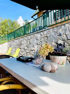 einen weißen Tisch mit Stühlen und eine Steinmauer in der Unterkunft Bloossom house in Bajina Bašta