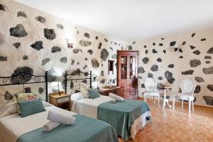 1 dormitorio con 2 camas y una pared con rocas en Casa Titi, en Las Indias